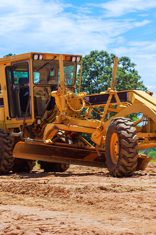 Niveleuse jaune sur chantier terrestre.