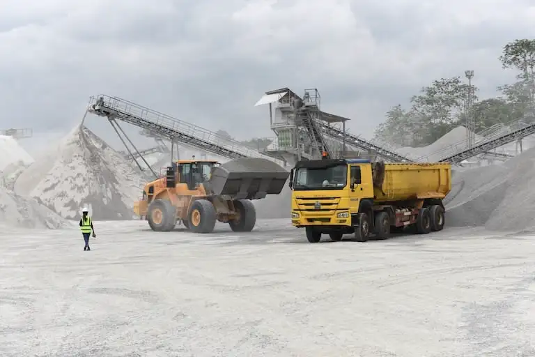 Camion et pelleteuse sur site industriel.