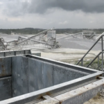 Ouvrier observant une carrière sous un ciel nuageux.