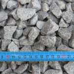 Cailloux gris avec règle bleue millimétrique.