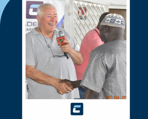 Homme souriant tenant un micro et serrant une main.