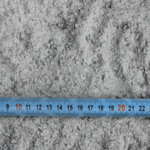 Mètre ruban bleu sur fond de sable gris.