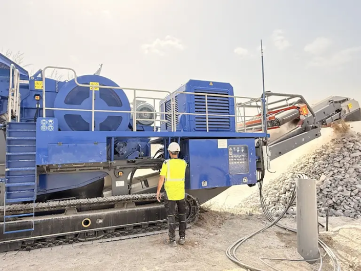 Ouvrier devant une machine industrielle en carrière.