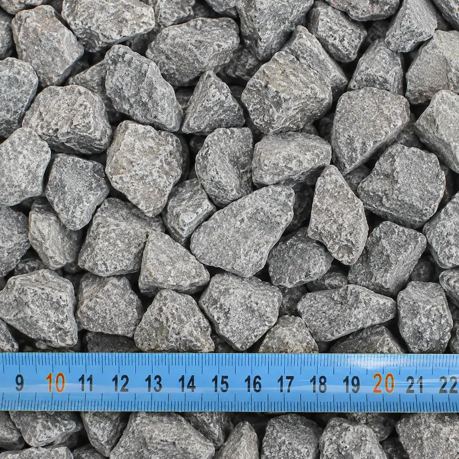 Pierres concassées avec mètre bleu en centimètres.